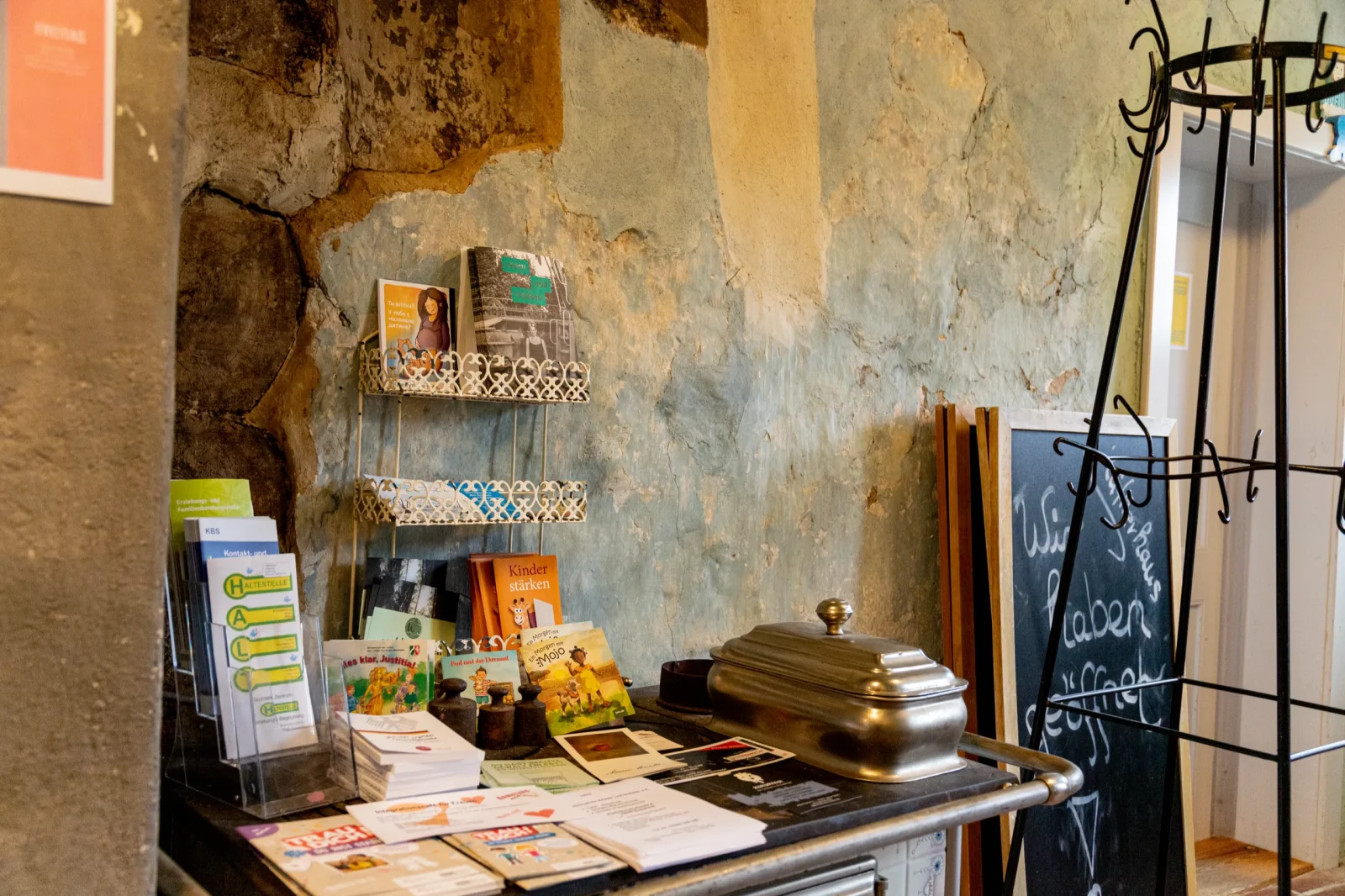 Ecke im Ehrenamtszentrum mit Flyern, Bücherregal und einer Kreidetafel